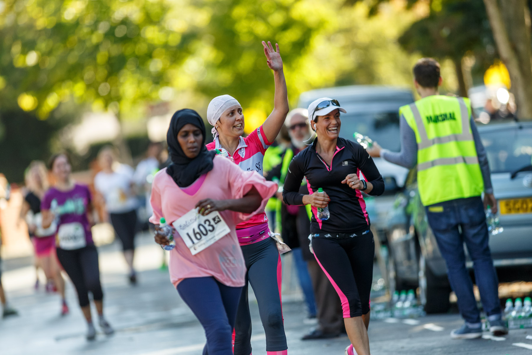 Diverse runners waving and smiling on the course