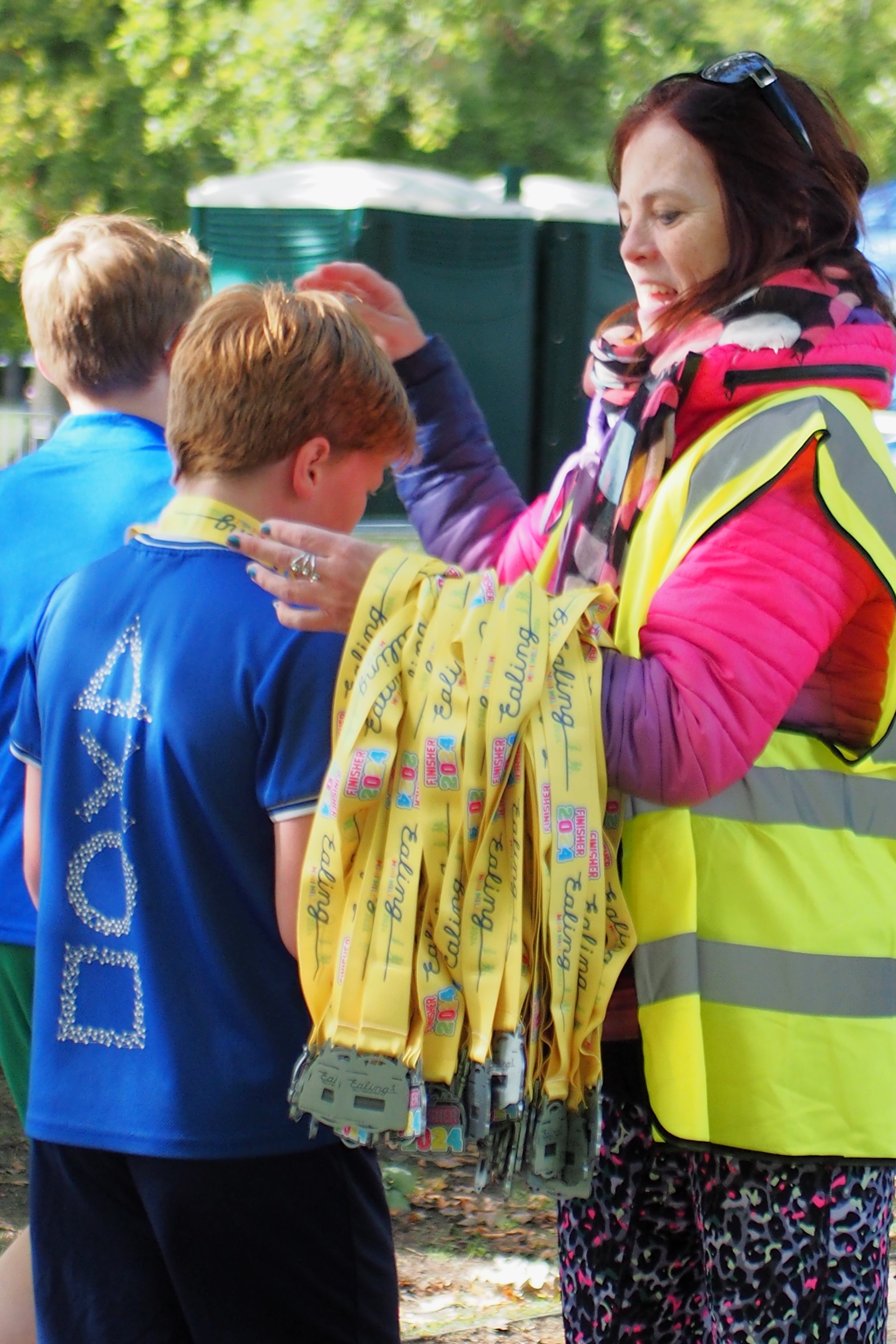Volunteer presenting finisher medals to young runners